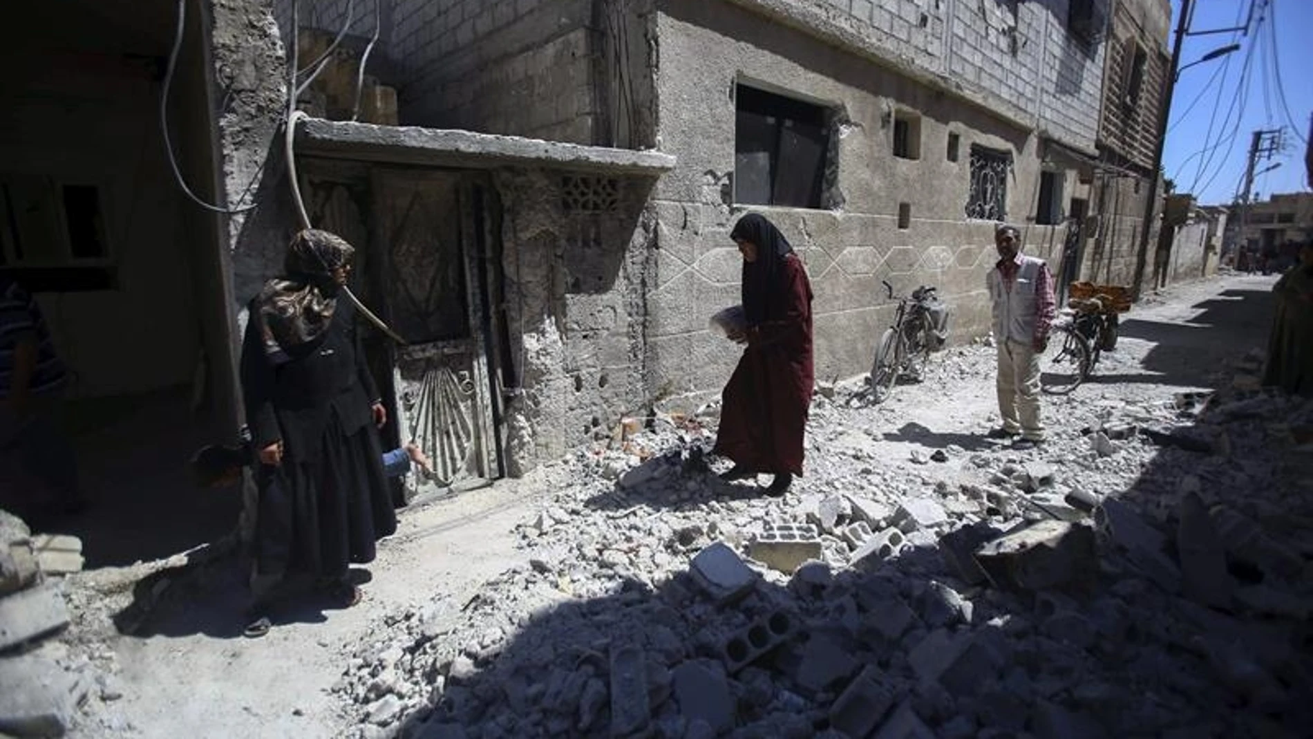 Varias personas inspeccionan edificios en ruinas tras los bombardeos en el pueblo de Deir al Asafi, al sureste de Damasco (Siria) Varias personas inspeccionan edificios en ruinas tras los bombardeos en el pueblo de Deir al Asafi, al sureste de Damasco (Siria)