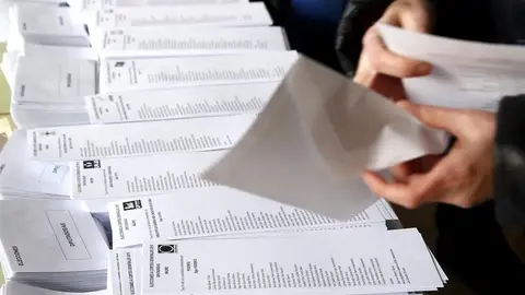 Una persona selecciona una de las papeletas dispuestas en el colegio electoral Una persona selecciona una de las papeletas dispuestas en el colegio electoral