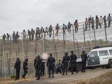 Inmigrantes sobre la valla de Melilla