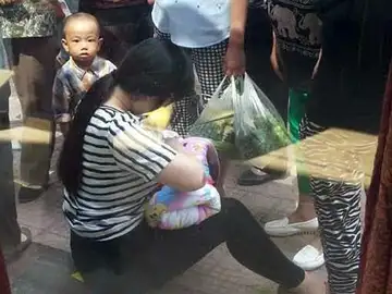 La mujer amamanta al pequeño en la calle La mujer amamanta al pequeño en la calle