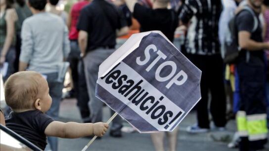 Un ni&ntilde;o sostiene un cartel de Stop desahucios, en una imagen de archivo.