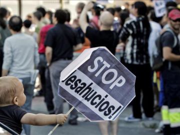 Un niño sostiene un cartel de Stop desahucios (Archivo)