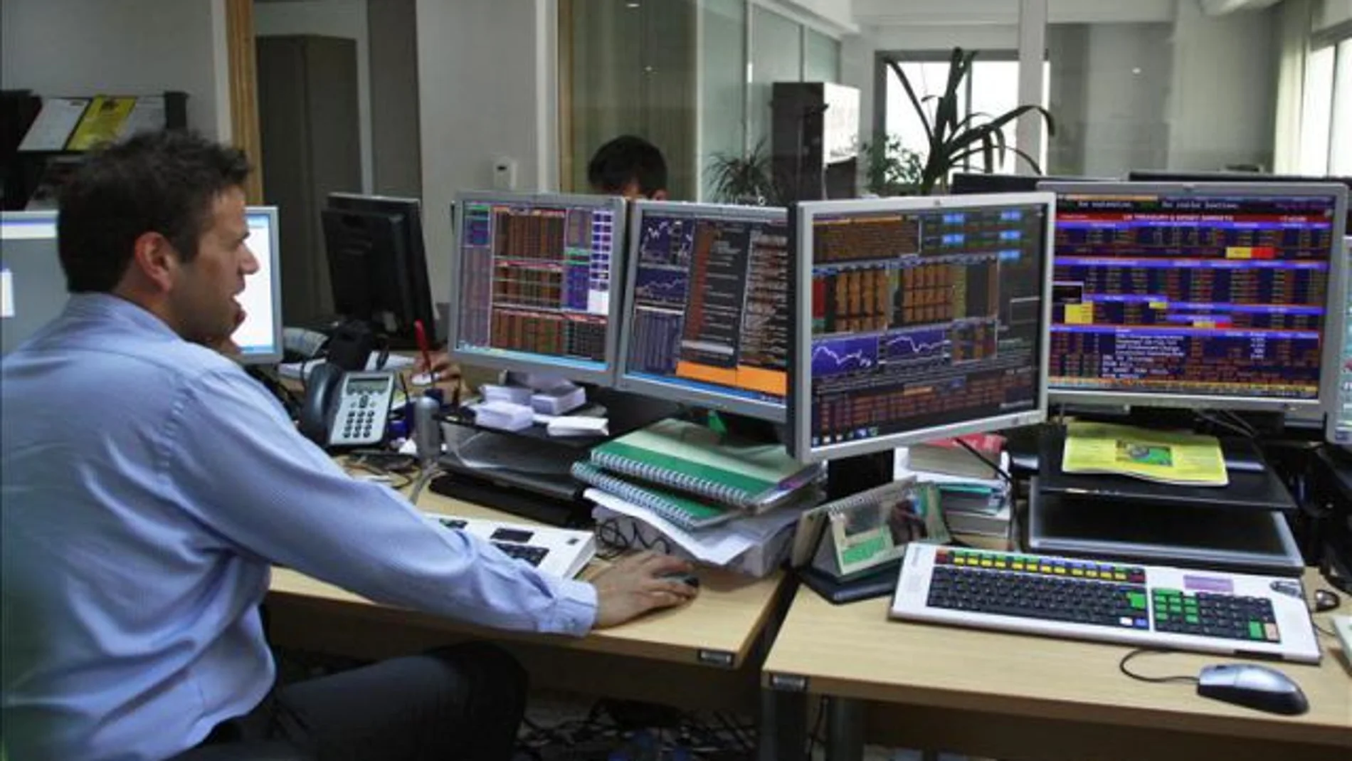 Un hombre trabaja frente a unos ordenadores Un hombre trabaja frente a unos ordenadores