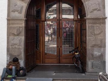 Un hombre pide limosna junto a la puerta de una iglesia