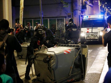 Varios antidisturbios retiran contenedores volcados en el barrio de Gràcia, en Barcelona