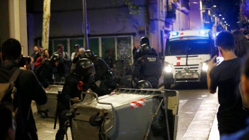 Varios antidisturbios retiran contenedores volcados en el barrio de Gràcia, en Barcelona