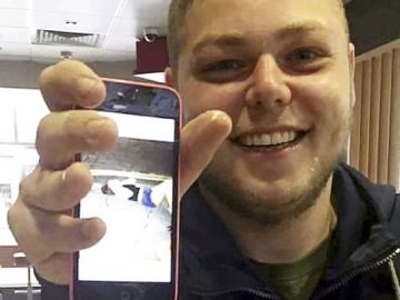 El joven sonriente posa con la imagen de su víctima.