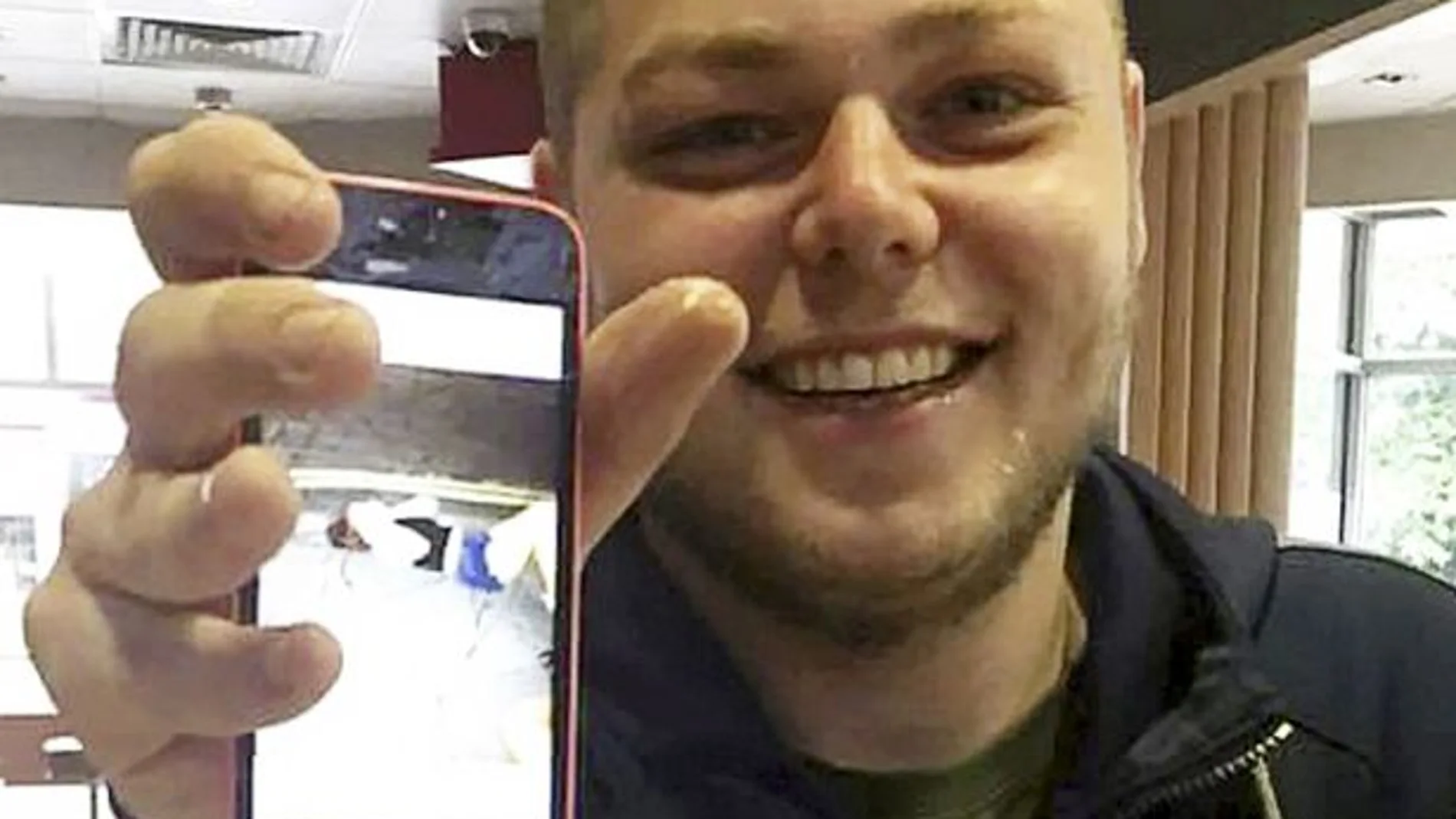 El joven sonriente posa con la imagen de su víctima. El joven sonriente posa con la imagen de su víctima.