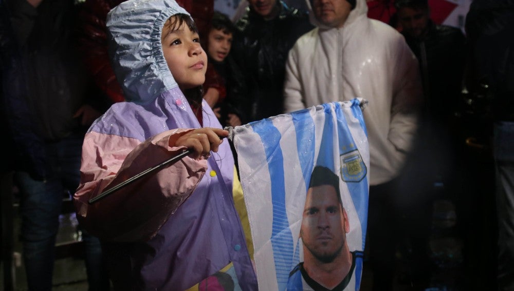 Un niño sostiene una bandera con la cara de Leo Messi