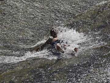 Un joven se refresca en el río Arga