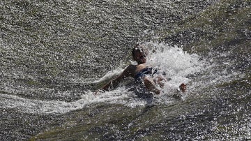 Un joven se refresca en el río Arga