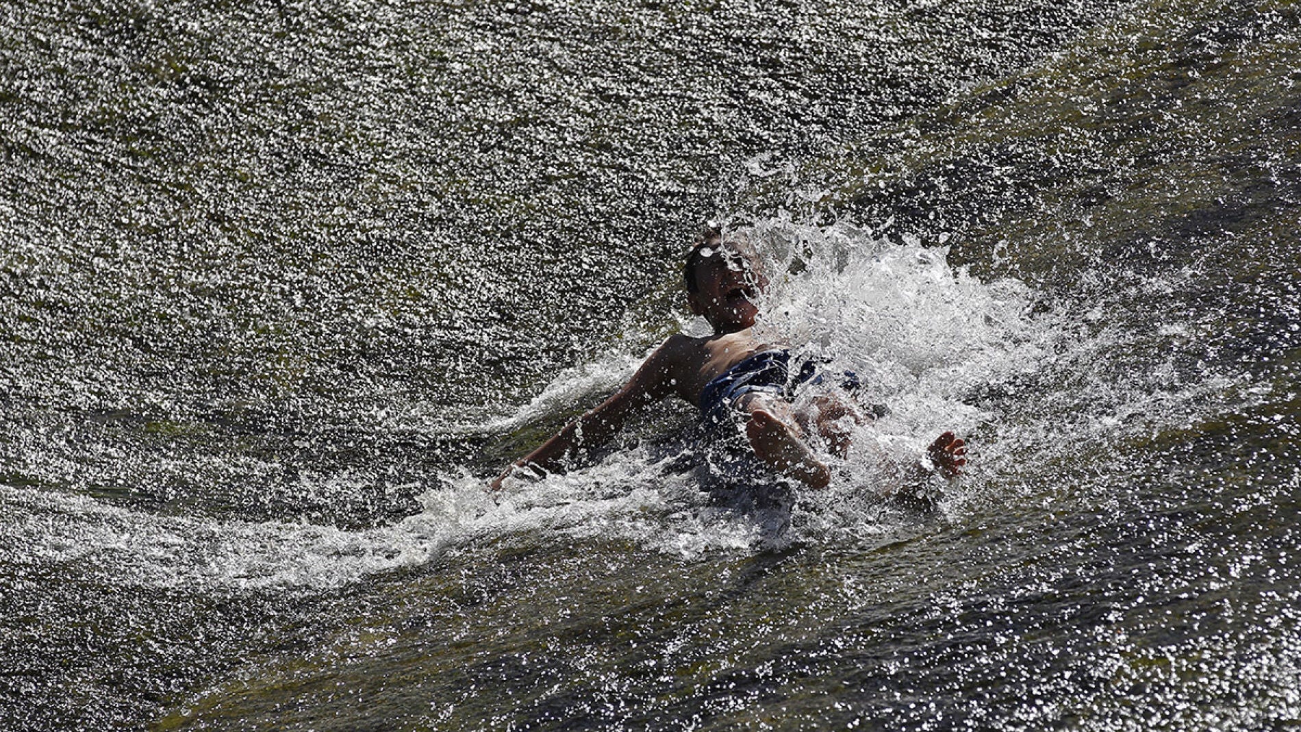 Un joven se refresca en el r&iacute;o Arga