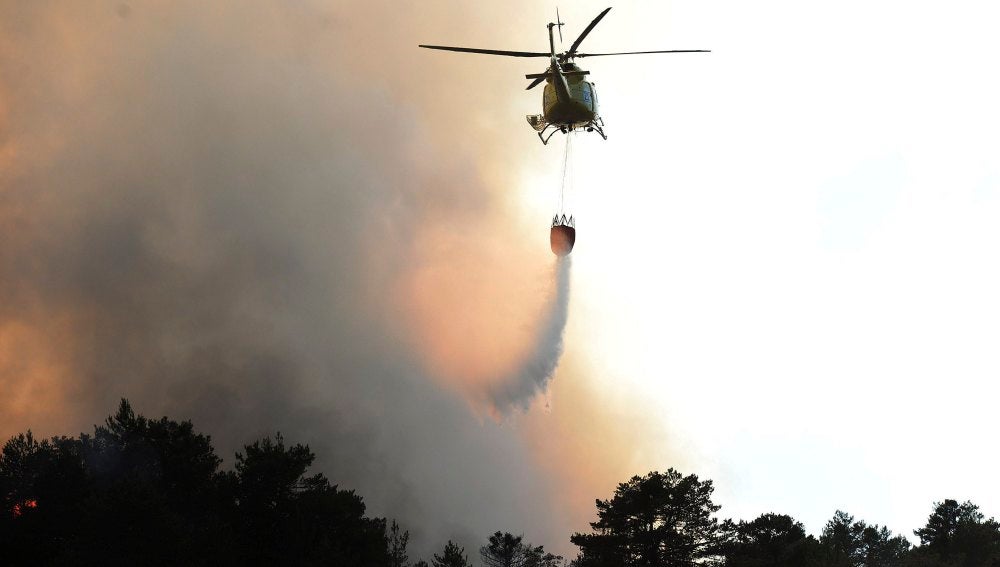 Un helicóptero descarga agua sobre un incendio 