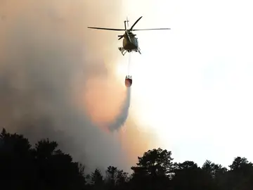 Un helicóptero descarga agua sobre un incendio Un helicóptero descarga agua sobre un incendio
