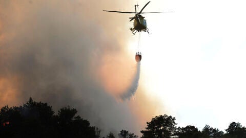 Un helic&oacute;ptero descarga agua sobre un incendio 