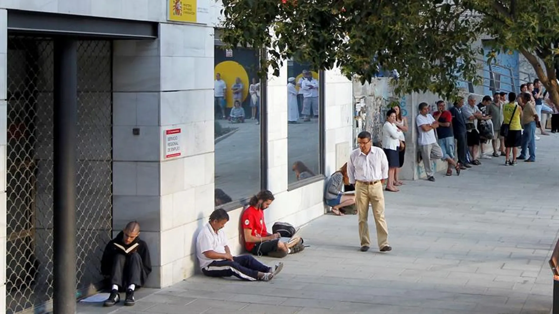 Imagen de la fachada de una Oficina de empleo con personas a la espera Imagen de la fachada de una Oficina de empleo con personas a la espera