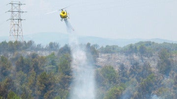 Un helicóptero remoja la zona afectada por un incendio forestal en un area boscosa en Segur de Calafellen (Tarragona)