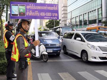  Un guardia de tráfico sostiene una pancarta en la que se lee "No juege a Pokemon Go mientras conduce"