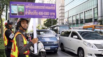  Un guardia de tráfico sostiene una pancarta en la que se lee "No juege a Pokemon Go mientras conduce"