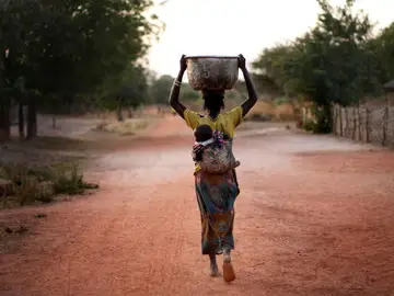 Mujer cargando con un cubo de agua Mujer cargando con un cubo de agua