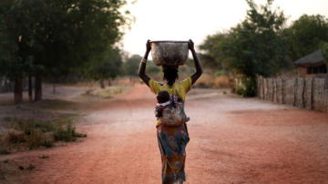 Mujer cargando con un cubo de agua