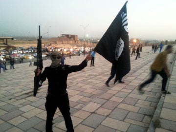 Un combatiente de Daesh sostiene una bandera y un arma en una calle de Mosul