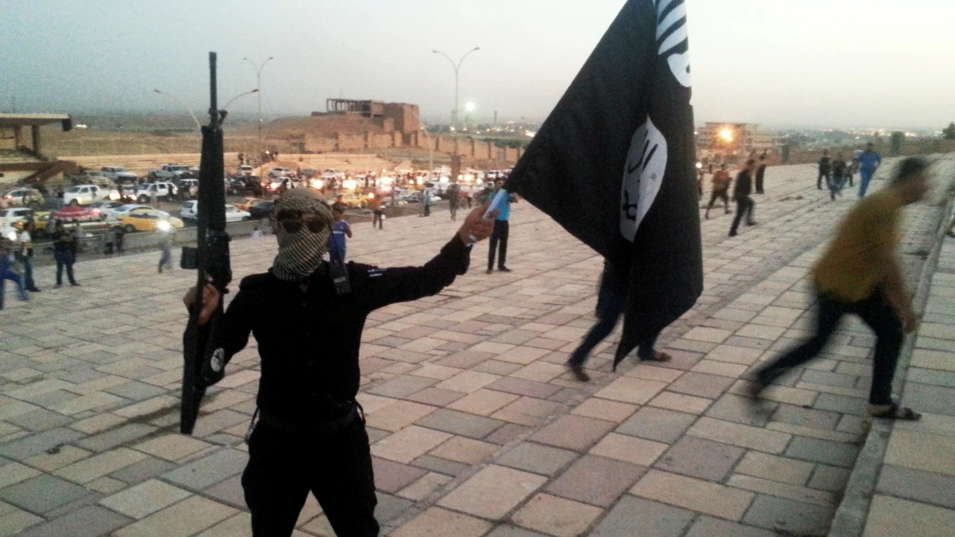 Un combatiente de Daesh sostiene una bandera y un arma en una calle de Mosul Un combatiente de Daesh sostiene una bandera y un arma en una calle de Mosul
