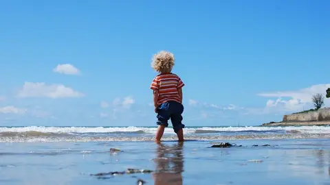 Un niño pequeño pasea en por la playa Un niño pequeño pasea en por la playa