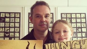 Padre e hija posan con dos dibujos