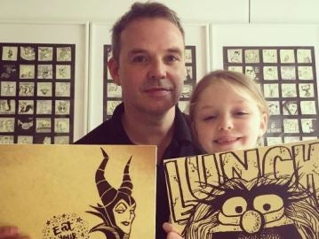 Padre e hija posan con dos dibujos Padre e hija posan con dos dibujos