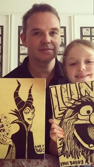 Padre e hija posan con dos dibujos Padre e hija posan con dos dibujos