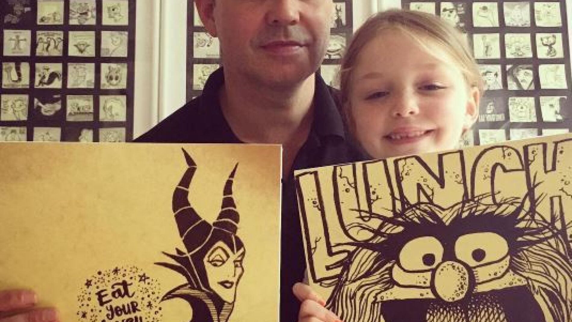 Padre e hija posan con dos dibujos