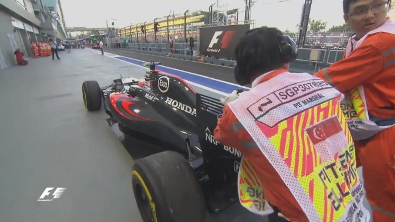 Los comisarios empujando el coche de Button en Singapur.