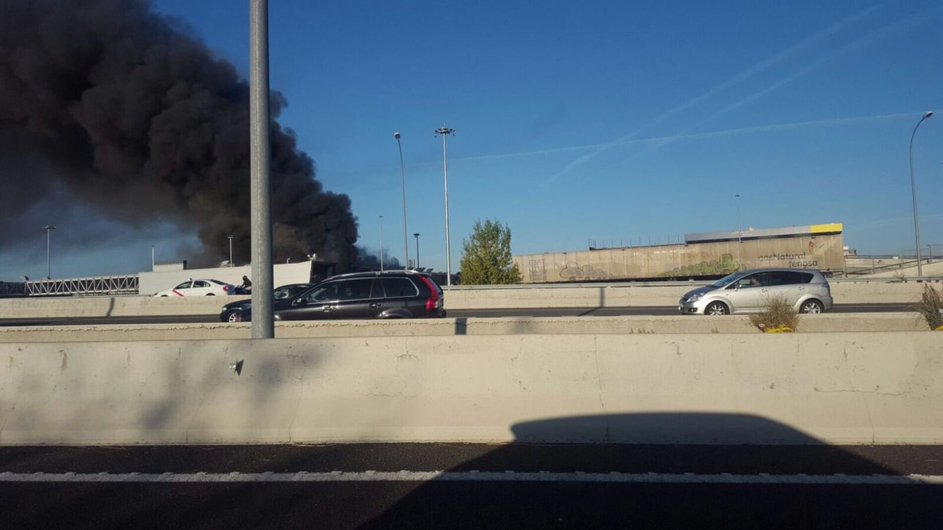 Columna de humo del incendio en una de las naves de la EMT en Sanchinarro.