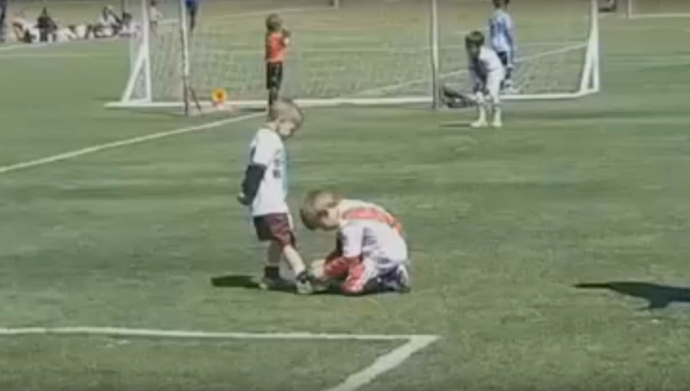 Un niño ayuda a otro a atarse la bota durante un partido en Argentina