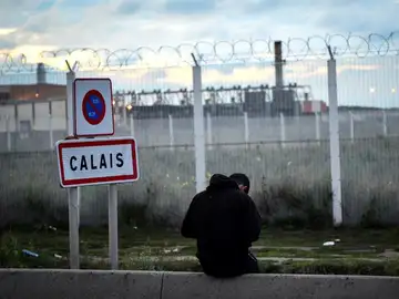 Un joven permanece sentado frente a una verja en del campamento de inmigrantes situado en Calais Un joven permanece sentado frente a una verja en del campamento de inmigrantes situado en Calais