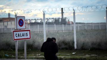 Un joven permanece sentado frente a una verja en del campamento de inmigrantes situado en Calais