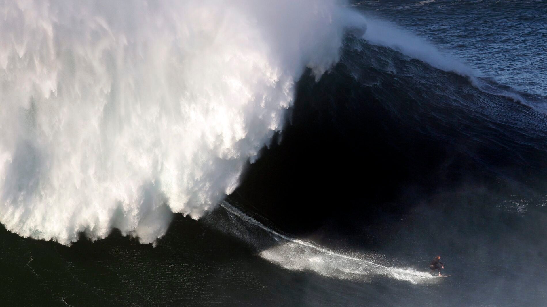 Un surfista desciende una ola en Nazar&eacute;