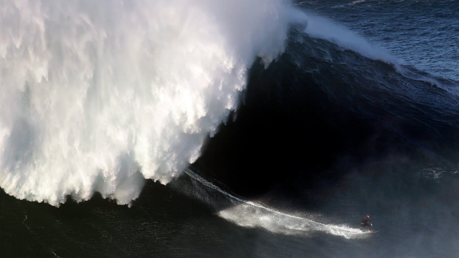 Un surfista desciende una ola en Nazaré Un surfista desciende una ola en Nazaré