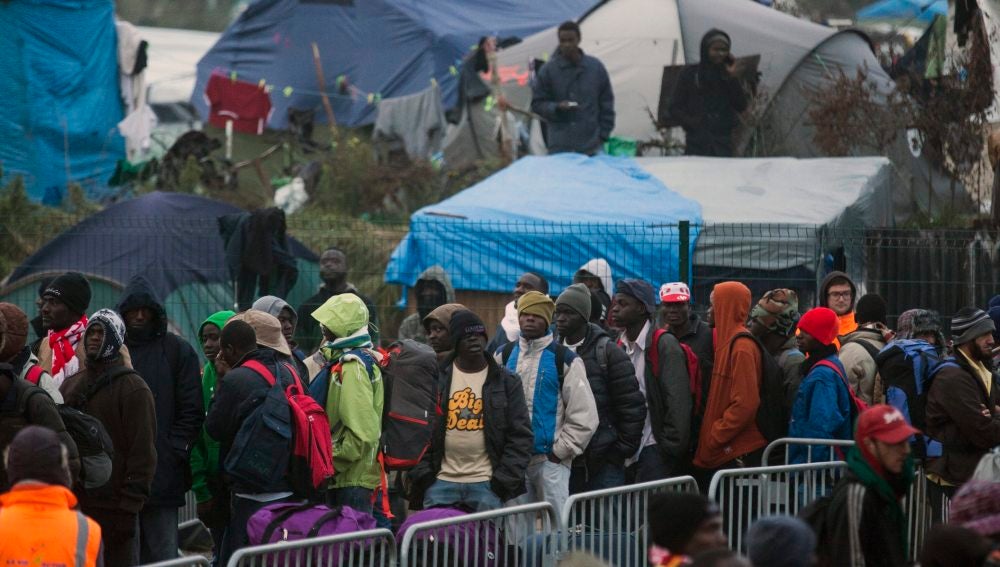 Varios migrantes esperan para su evacuación en el centro de recepción de corta estancia en el campamento conocido como "La Jungla" durante su desmantelamiento en Calais