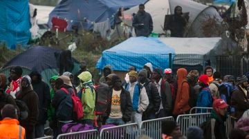 Varios migrantes esperan para su evacuación en el centro de recepción de corta estancia en el campamento conocido como "La Jungla" durante su desmantelamiento en Calais
