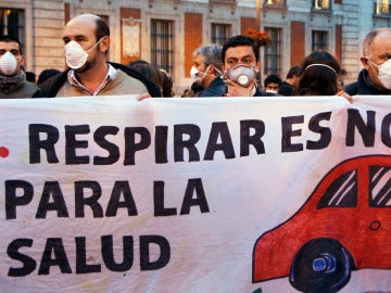 La gente usa máscaras y sostienen una pancarta durante un flashmob para marcar el problema de la contaminación en el centro de Madrid