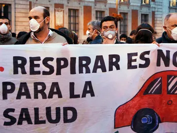 La gente usa máscaras y sostienen una pancarta durante un flashmob para marcar el problema de la contaminación en el centro de Madrid La gente usa máscaras y sostienen una pancarta durante un flashmob para marcar el problema de la contaminación en el centro de Madrid