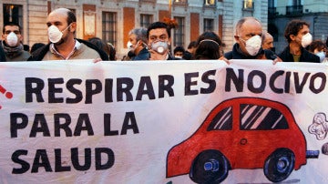 La gente usa máscaras y sostienen una pancarta durante un flashmob para marcar el problema de la contaminación en el centro de Madrid