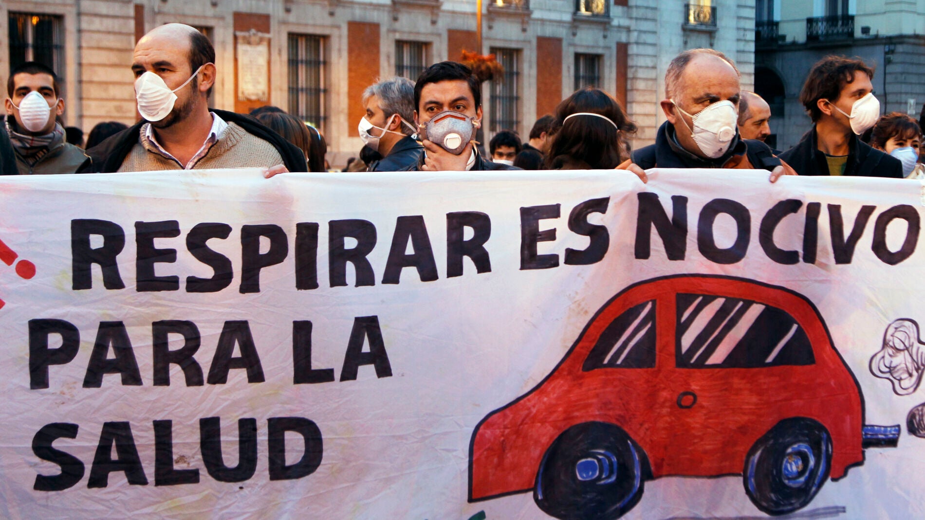 La gente usa m&aacute;scaras y sostienen una pancarta durante un flashmob para marcar el problema de la contaminaci&oacute;n en el centro de Madrid
