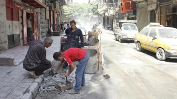 Tres hombres recogen los escombros producidos tras el lanzamiento de un cohete en varios puntos del norte de Alepo, Siria