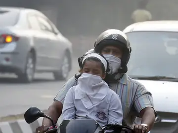 Un hombre y su hijo circulan en bicicleta protegidos con máscaras en Nueva Delhi Un hombre y su hijo circulan en bicicleta protegidos con máscaras en Nueva Delhi
