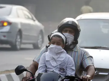 Un hombre y su hijo circulan en bicicleta protegidos con máscaras en Nueva Delhi Un hombre y su hijo circulan en bicicleta protegidos con máscaras en Nueva Delhi
