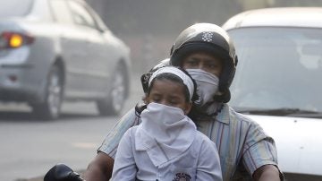 Un hombre y su hijo circulan en bicicleta protegidos con máscaras en Nueva Delhi