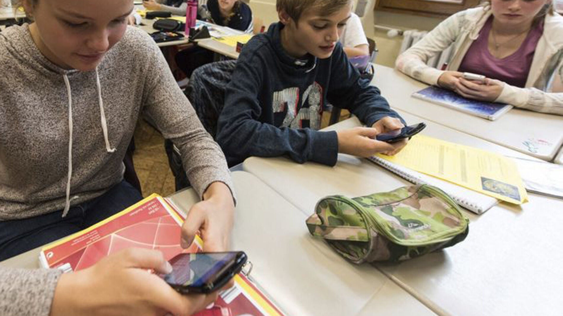 Unos alumnos utilizan el smartphone en clase